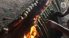 Pekerja membakar lemang di kawasan Kwitang, Jakarta, Minggu (9/3/2025). (Liputan6.com/Herman Zakharia)