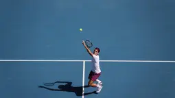 Petenis Swiss, Roger Federer, melakukan servis saat melawan petenis AS, Tennys Sandgren, pada perempat final Australia Open 2020 di Melbourne, Selasa (28/1). Federer menang 6-3, 2-6, 2-6, 7-6 (10-8), 6-3 atas Sandgren. (AFP/David Gray)