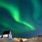 Aurora Borealis menerangi langit malam di atas rumah-rumah penduduk di Nuuk, Greenland, pada 23 Januari 2026. Cahaya hijau bersinar menghiasi langit kota Nuuk, Greenland, pada Jumat 23 Januari 2026 waktu setempat. (Jonathan NACKSTRAND/AFP)