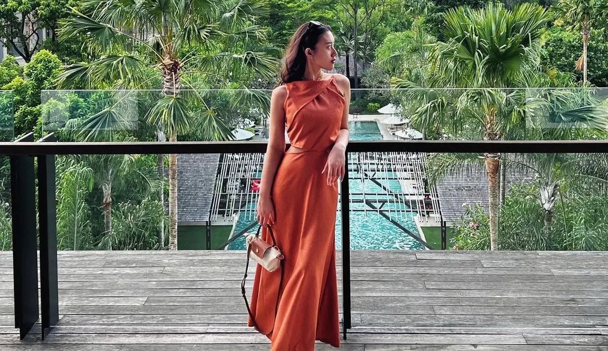 Mengenakan dress coral sleeveless cut out di bagian pinggang, Kusuma Puteri membawa mini bag dari Longchamp warna putih.  [@kusumaputeri]