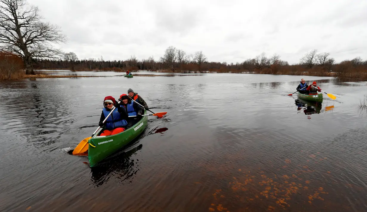 Pengunjung bermain kayak di tengah banjir yang merendam padang rumput Taman Nasional Soomaa, Estonia, Minggu (17/3). Banjir akibat salju yang mencair kerap merendam Taman Nasional Sooma memasuki musim semi. (Reuters/Ints Kalnins)