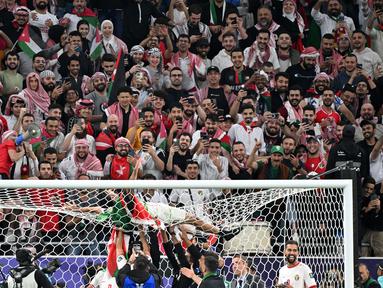 Pemain Yordania, Yazan Al-Naimat merayakan kemenangan timnya atas Korea Selatan dengan menaiki gawang setelah laga semifnial Piala Asia 2023 di Ahmad Bin Ali Stadium, Doha, Qatar, Selasa (06/02/2024). (AFP/Hector Retamal)