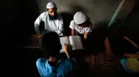 Seorang anak serius membaca Al-Quran saat di sebuah madrasah lokal selama bulan Ramadan di Srinagar, Kashmir yang dikuasai India, (30/5). Di bulan puasa umat muslim menahan diri untuk tidak makan dan minum. (AP Photo / Mukhtar Khan)