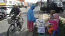 Seorang ibu ditemani anaknya melayani pembeli saat berjualan masker kain buatan rumahan di Jalan Raya Cinere-Depok, Limo, Depok, Rabu (8/4/2020). Dalam sehari ia  mampu menjual rata-rata 300 masker kain. (merdeka.com/Arie Basuki)