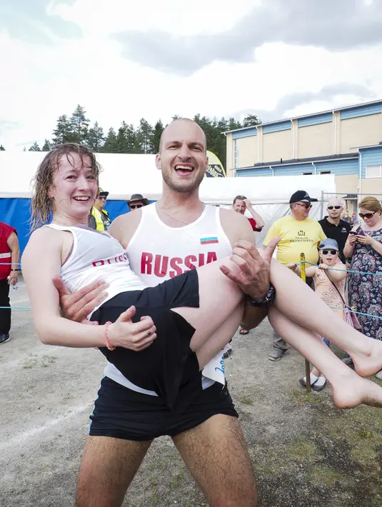 Peserta dari Rusia, Anastasia Loginova dan Dimitriy Sagal keluar sebagai juara kompetisi Wife Carrying World Championships di Sonkajarvi, Finlandia, 2 Juli 2016. Lomba unik ini digelar bulan Juli tiap tahunnya. (Timo Hartikainen/Lehtikuva/AFP)