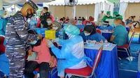 Seorang personel TNI AL menenangkan salah satu peserta vaksinasi Covid-19 yang takut disuntik di acara serbuan vaksin secara massal di Stadion Gajayana, Kota Malang, pada Sabtu, 7 Agustus 2021 (Liputan6.com/Zainul Arifin)