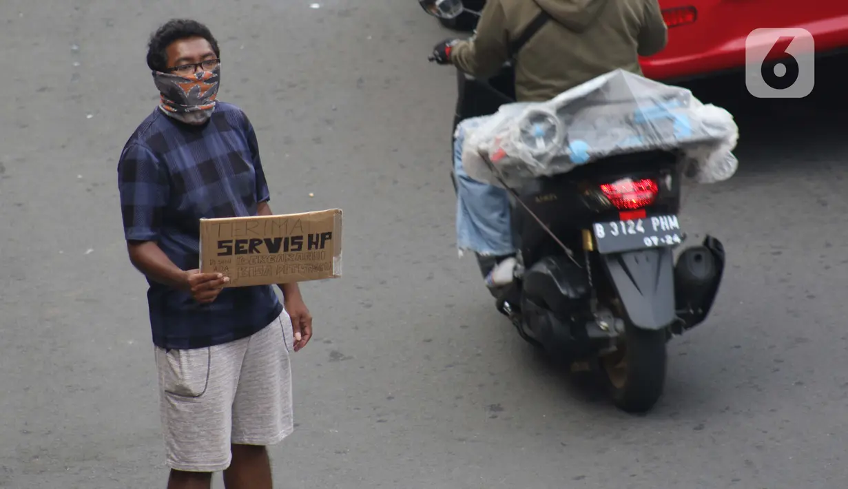Penjual jasa perbaikan telepon genggam menawarkan jasanya di depan Mall Pusat Grosir Cililitan, Jakarta, Kamis (14/5/2020). Sejak pemberlakuan Pembatasan Sosial Berskala Besar yang berimbas pada penutupan pusat-pusat perbelanjaan, pendapatan mereka turun drastis. (Liputan6.com/Helmi Fithriansyah)