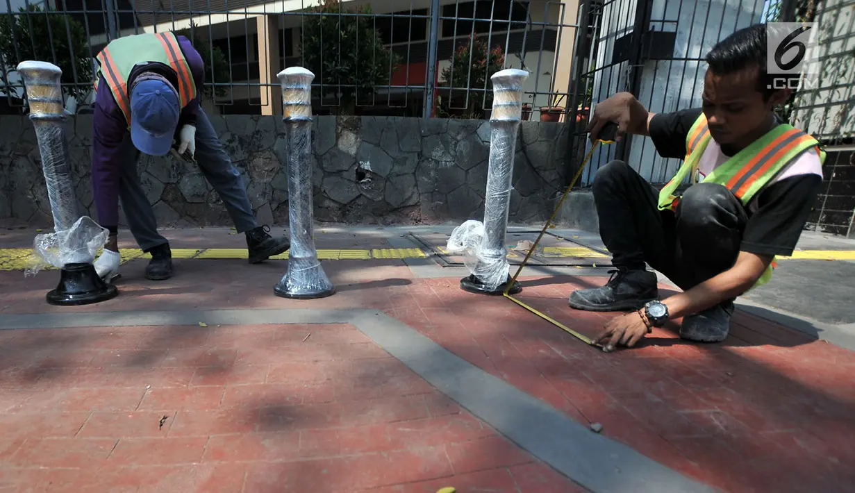 Pekerja memasang Bolar atau tiang pembatas pedestrian di kawasan Tugu Tani, Jakarta, Minggu (9/9). Pemasangan Bolar bertujuan menjaga keindahan jalur pedestrian dan mencegah penyalahgunaan fungsi.(merdeka.com/ Iqbal S. Nugroho)