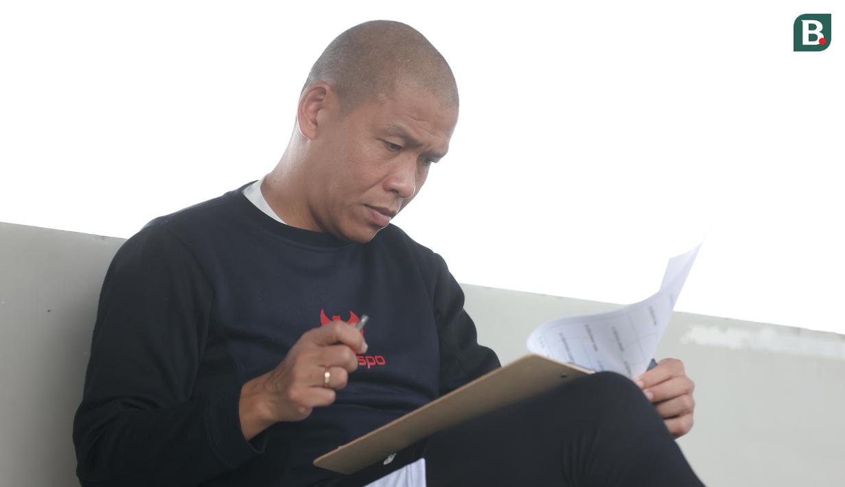 Pelatih Timnas Indonesia U-16, Nova Arianto memeriksa berkas sebelum memimpin anak asuhnya berlatih di lapangan latihan Jakarta International Stadium (JIS), Jakarta, Minggu (31/03/2024) sore. (Bola.com/Abdul Aziz)