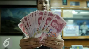 Petugas menunjukkan uang pecahan 100 Yuan di tempat penukaran uang, Jakarta, Kamis (13/8/2015). Kebijakan Tiongkok yang sengaja melemahkan (devaluasi) mata uang Yuan membuat Rupiah melemah terhadap dolar AS. (Liputan6.com/Johan Tallo)