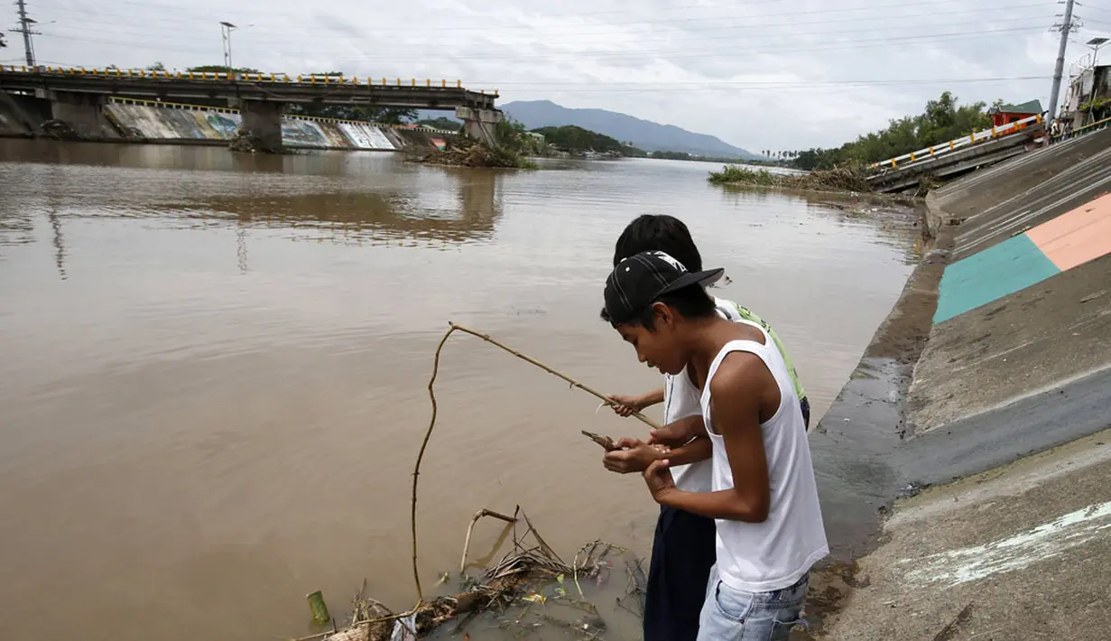 Beberapa anak terlihat memancing di tepian sungai dekat jembatan yang hancur saat serangan topan Rammasun, di Batangas, Manila, (17/7/2014). (REUTERS/Erik De Castro)