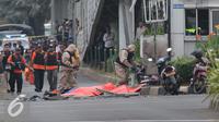 Petugas menutup mayat korban ledakan bom di pos pol sarinah, Jakarta, Kamis, (14/1/2016). Beberapa ledakan dan suara senjata api terjadi di pusat ibukota Indonesia, Polisi mencurigai seorang melakukan aksi bom bunuh diri. (Liputan6.com/Angga Yuniar)