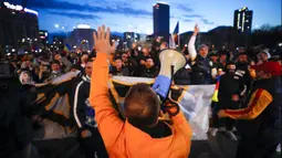 Warga yang memprotes pembatasan terkait pandemi COVID-19 meneriakkan slogan di luar markas pemerintah di Bucharest, Rumania, Senin (29/3/2021). Ribuan pengunjuk rasa antipembatasan turun ke jalan di beberapa kota di Rumania sehari setelah langkah pembatasan baru diberlakukan. (AP Photo/Vadim Ghirda)
