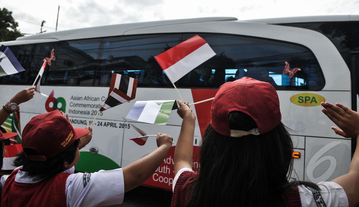 Para pelajar melambaikan bendera negara menyambut kedatangan Para kepala Negara dan delegasi dari Asia dan Afrika mengikuti 'Historical Walk' dalam rangkaian Peringatan KAA ke-60, di Bandung, Jumat (24/4/2015). (Liputan6.com/Faizal Fanani)