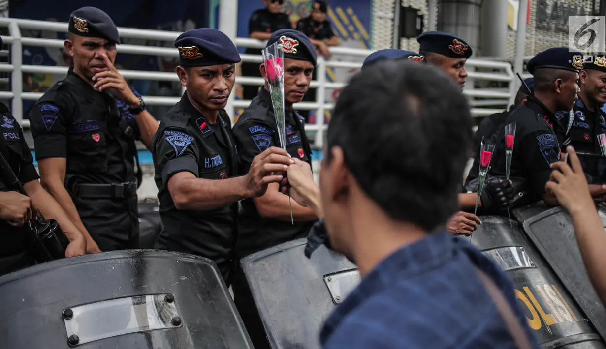 Petugas Brimob menerima bunga dari peserta aksi komunitas Spartan Nusantara di sekitar Gedung Bawaslu, Jakarta, Minggu (26/5/2019). Aksi tersebut sebagai bentuk terima kasih kepada TNI/Polri karena setia dan menjaga keamanan NKRI terkait sengketa pemilu. (Liputan6.com/Faizal Fanani)