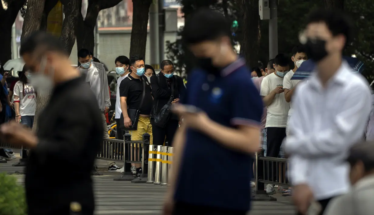 Orang-orang yang mengenakan masker mengantre untuk tes virus corona COVID-19 di tempat pengujian pada hari ketiga pengujian massal untuk jutaan penduduk di Distrik Chaoyang, Beijing, China, 15 Juni 2022. (AP Photo/Mark Schiefelbein)