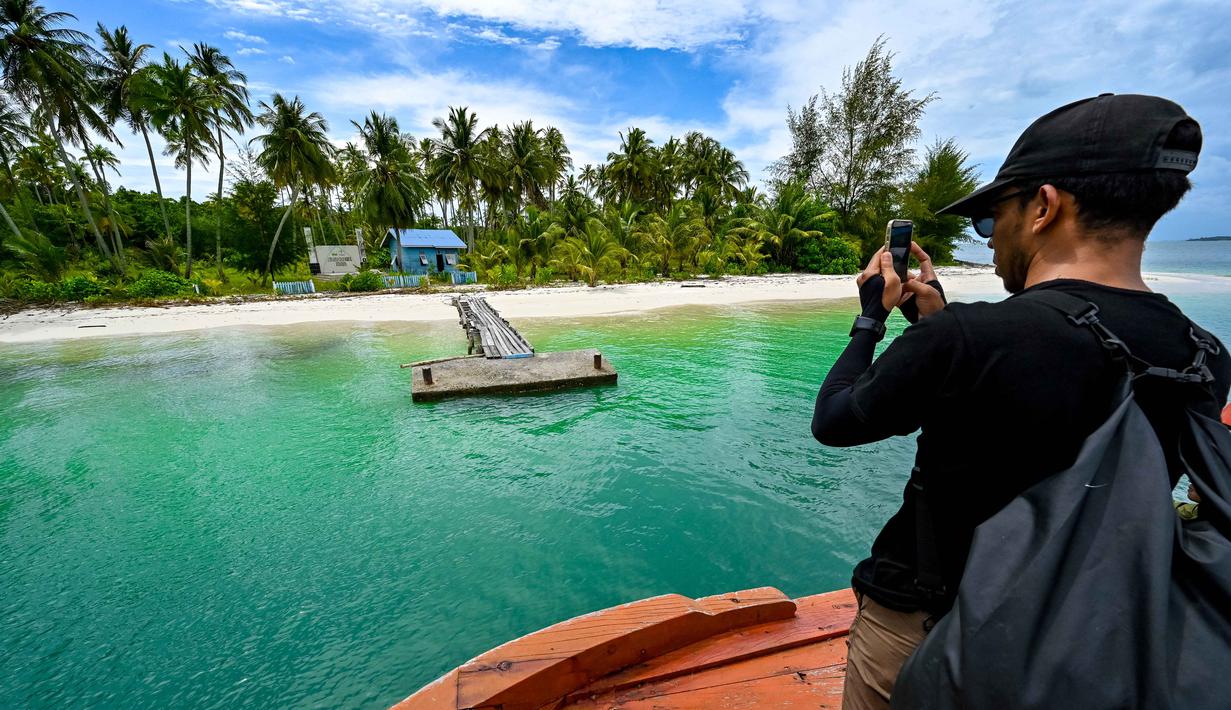 Namun, sengketa tersebut telah tuntas dengan keputusan pemerintah pusat yang menetapkan keempat pulau tersebut sebagai bagian dari wilayah administratif Provinsi Aceh. Tampak dalam foto, seorang pria mengambil foto Pulau Panjang, yang pernah menjadi objek sengketa batas pulau antara Aceh dan Sumatra Utara, di Singkil, Provinsi Aceh bagian selatan, pada Rabu 12 November 2025. (CHAIDEER MAHYUDDIN/AFP)