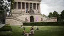 Orang-orang beristirahat pada hari musim panas di sebuah taman di depan museum Alte Nationalgalerie di Berlin, Jerman, Minggu (19/6/2022). Orang-orang berbondong-bondong ke taman dan kolam renang di seluruh Eropa Barat untuk sedikit mendinginkan tubuh mereka dari gelombang panas awal. (AP Photo/Markus Schreiber)