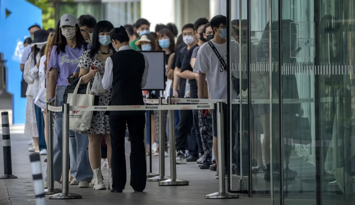 Karyawan yang mengenakan masker menunggu hasil tes COVID-19 mereka diperiksa untuk memasuki gedung perkantoran di kawasan pusat bisnis di Beijing, China, Selasa (31/5/2022). Penguncian COVID-19 di Shanghai telah mencekik ekonomi nasional dan sebagian besar mengurung jutaan orang di rumah mereka. (AP Photo/Mark Schiefelbein)