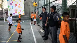 Polisi ikut bermain bola voli saat menjaga Anak-anak pada program Volleyball Development Training yang digagas oleh Federasi Bola Voli Internasional di Formiga favela, Rio de Janeiro, (2/8/2016). (AFP/Leon Neal)