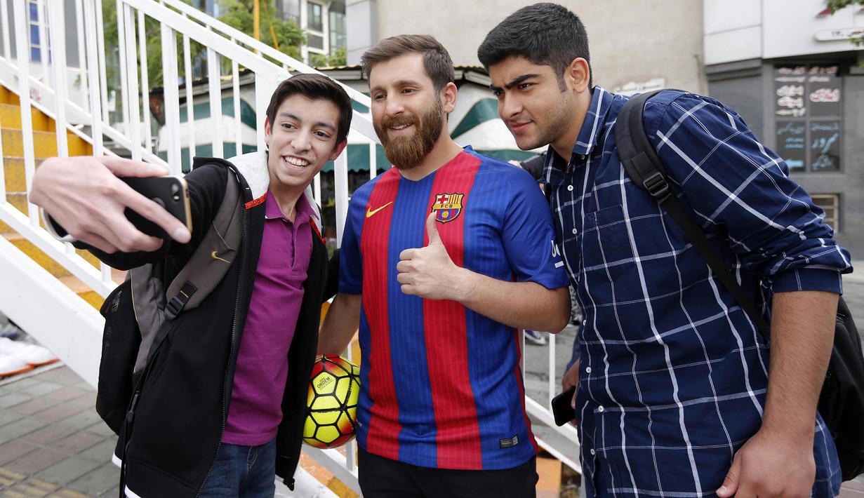Reza Parastesh, seorang warga Iran yang memiliki wajah mirip Lionel Messi diajak selfie oleh warga di jalanan Tehran, Iran, Senin (8/5/2017). (AFP/Atta Kenare)