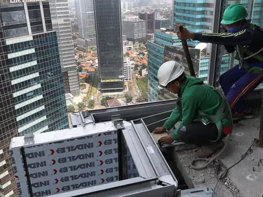 Pekerja Nusa Konstruksi Enjiniring memasang kaca gedung World Capital Tower, di Mega Kuningan, Jakarta, Rabu (13/9). Deretan gedung perkantoran masih menghiasi di ibukota Jakarta. (Liputan6.com/Fery Pradolo)
