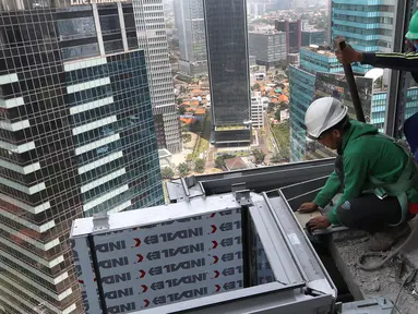 Pekerja Nusa Konstruksi Enjiniring memasang kaca gedung World Capital Tower, di Mega Kuningan, Jakarta, Rabu (13/9). Deretan gedung perkantoran masih menghiasi di ibukota Jakarta. (Liputan6.com/Fery Pradolo)