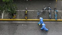 Petugas kesehatan yang mengenakan alat pelindung diri (APD) berjalan di jalan saat lockdown akibat virus corona COVID-19 di Distrik Jing'an, Shanghai, China, Sabtu (16/4/2022). (Hector RETAMAL/AFP)