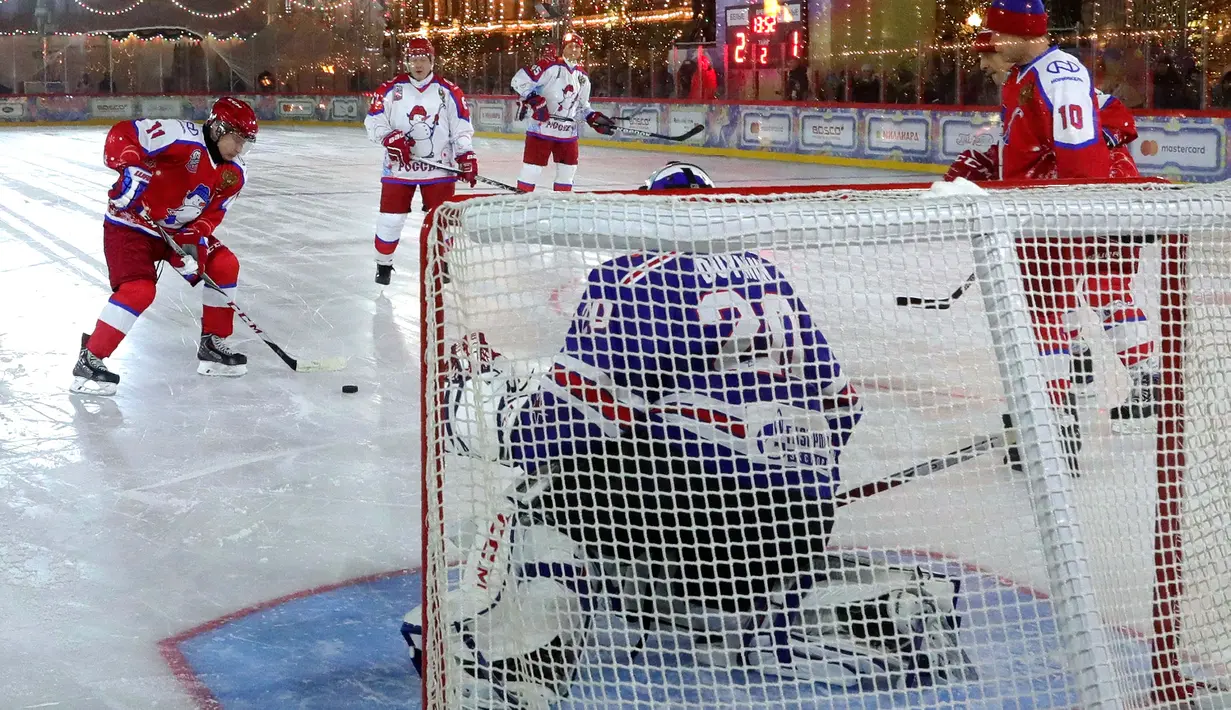 Presiden Rusia Vladimir Putin mencoba mencetak gol saat pertandingan eksihibisi Night Hockey League di gelanggang es di Lapangan Merah, Moskow, Rabu (25/12/2019). Night Hockey  merupakan turnamen berisi gabungan klub dan pemain amatir. (Mikhail Klimentyev, Sputnik, Kremlin Pool via AP)