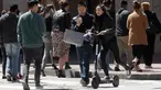 Seorang wanita menyebrang jalanan mengendarai skuter bermotor di San Francisco (17/4). San Francisco menghentikan operasi perusahaan yang menyewakan skuter bermotor. (AP/Jeff Chiu)