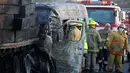 Petugas pemadam kebakaran berada di lokasi kecelakaan antara sebuah van dan truk kargo  di jalan raya Negara Bagian Jalisco, Meksiko, Rabu (18/12/2019). Korban tewas kebanyakan karena terjebak di dlaam mini bus yang terbakar setelah menabrak truk bermuatan kayu. (Ulises Ruiz / AFP)