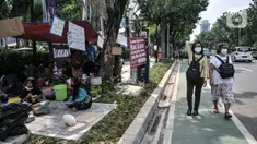 Warga korban gusuran Kampung Bayam mendirikan tenda darurat saat menggelar aksi di depan Balai Kota, Jakarta, Senin (5/12/2022). Dengan membawa terpal dan perabotan rumah tangga, puluhan korban gusuran Kampung Bayam kembali membangun tenda darurat di depan Balai Kota untuk menuntut PT Jakarta Propertindo (JakPro) segera menyerahkan kunci hunian Kampung Susun Bayam (KSB) serta memberikan harga sewa yang murah. (merdeka.com/Iqbal S. Nugroho)