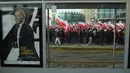 Orang-orang mengibarkan bendera nasional Polandia berjalan melewati iklan film James Bond saat pawai untuk menandai Hari Kemerdekaan Nasional Polandia di Warsawa, Polandia, 11 November 2021. Hari Kemerdekaan Nasional Polandia dirayakan pada 11 November. (Adam Chelstowski/AFP)
