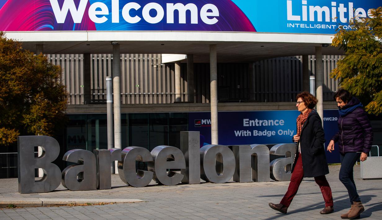 Orang-orang berjalan melewati poster yang mengumumkan Mobile World Congress (MWC) 2020 di lokasi pameran di Barcelona, Spanyol, Selasa (11/2/2020). Pembatalan MWC 2020 dilakukan setelah diadakannya pertemuan darurat oleh para petinggi penyelenggara. (AP Photo/Emilio Morenatti)