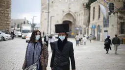 Wanita dan pria mengenakan masker berjalan di luar Kota Tua Yerusalem di tengah pandemi COVID-19 (25/11/2020). (Xinhua/Muammar Awad)