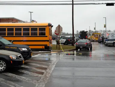Sejumlah kendaraan dari petugas keamanan dan bus sekolah terparkir di dekat pintu masuk Great Mills High School di Maryland, AS (20/3). Seorang pelaku penembakan bernama Austin Wyatt Rollins melukai dua siswa di sekolah tersebut. (AP Photo / Alex Brandon)
