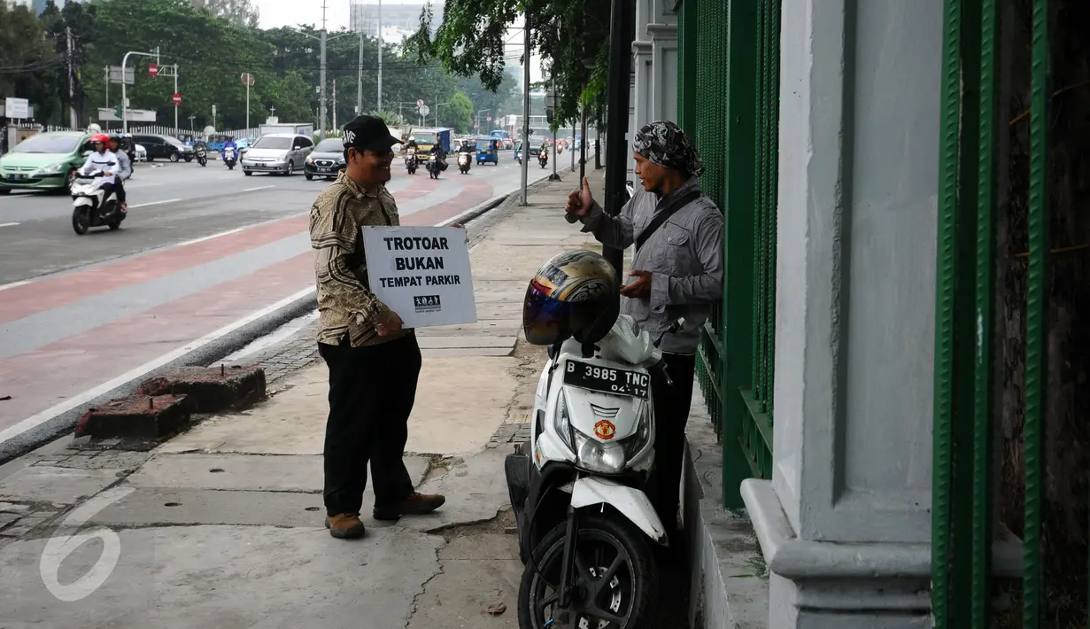 Perwakilan komunitas peduli pejalan kaki menegur pengguna motor yang parkir di trotoar Jalan Medan Merdeka Timur, Jakarta, Jumat (17/3). Mereka menghimbau pengguna motor untuk tidak melewati dan parkir di trotoar jalan. (Liputan6.com/Helmi Fithriansyah)
