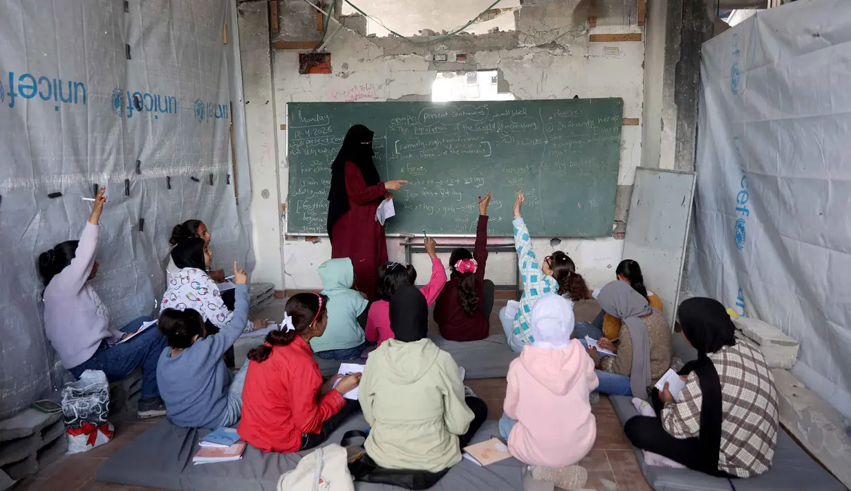 Data dari UNICEF pada November 2025 bahkan mencatat angka yang lebih tinggi, yaitu 97% sekolah mengalami kerusakan dalam berbagai tingkat. Tampak dalam foto, anak-anak pengungsi Palestina mengikuti belajar mengajar di dalam tenda di Sekolah Mada, kamp pengungsi Jabalia, Jalur Gaza Utara pada 13 April 2026. (Omar AL-QATTAA/AFP)