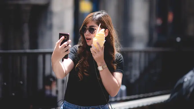 perempuan memegang smartphone