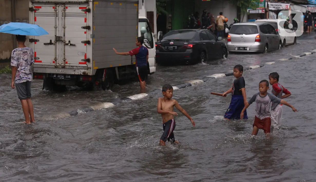 Sejumlah anak bermain banjir saat melanda jalan Bayangkara Pusdiklat, Kota Tangerang Selatan, Banten, Selasa (2/11/2021). Aksi anak anak tersebut dapat membahayakan keselamatan jiwa karena banyaknya kendaraan yang melintas menerjang banjir. (Liputan6.com/Angga Yuniar)