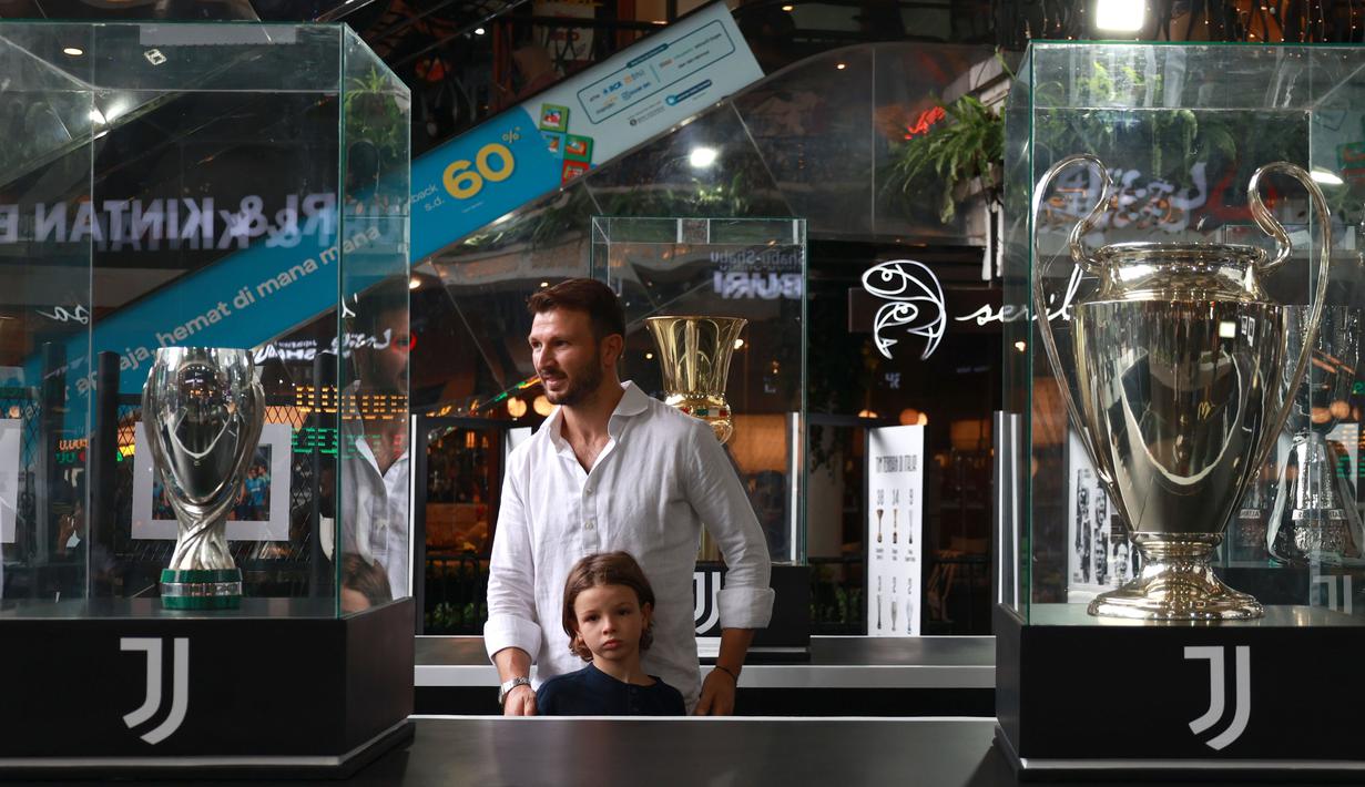 Tak hanya Edgar Davids, Marco Motta yang membawa buah hatinya juga melihat satu persatu trofi asli yang dibawa dari museum milik Juventus. (Bola.com/Ikhwan Yanuar)