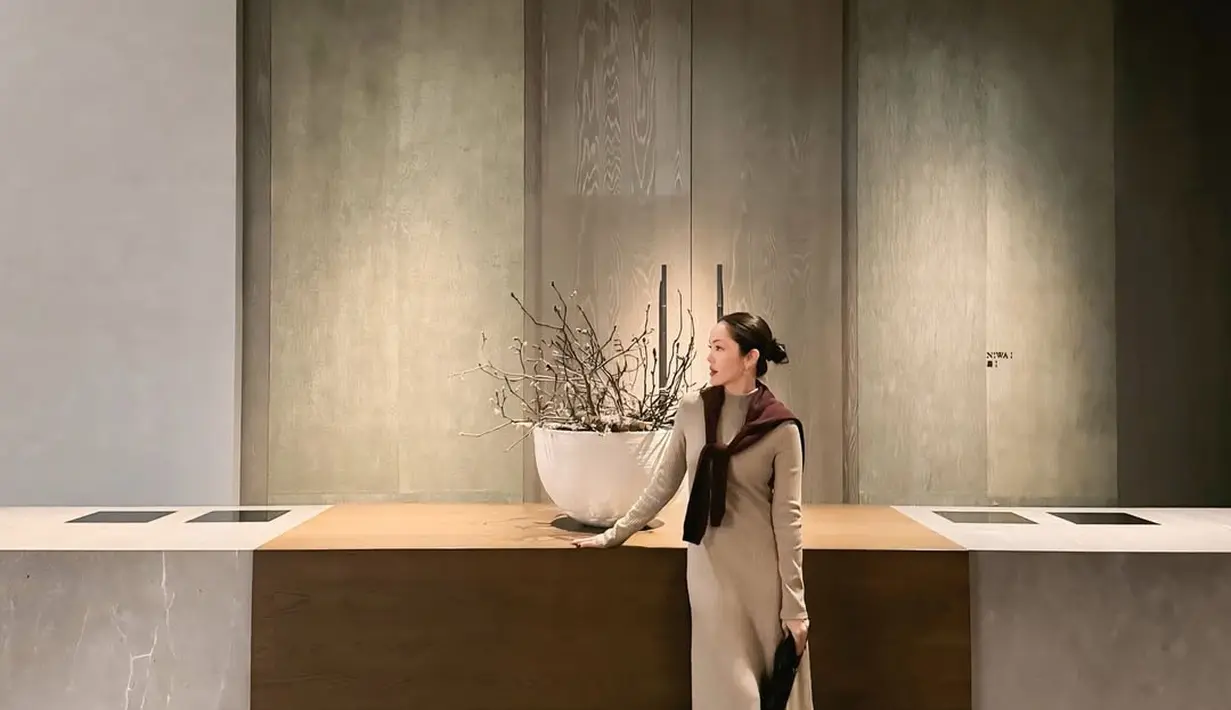 Pada potret lainnya, Cathy mengenakan rib knit turtleneck dress yang terlihat sangat chic. Ia melengkapi penampilannya dengan cardigan yang cukup diikat di bahu untuk memberikan sentuhan effortless elegance. Sepasang boots hitam menjadi pilihan alas kaki yang melengkapi gaya ini dengan sempurna. [@cathysharon].