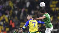 Cristiano Ronaldo dari Al Nassr (tengah) melompat berebut bola dengan pemain Al Ettifaq selama pertandingan Liga Pro Saudi di Stadion Mrsool Park, di Riyadh, Arab Saudi, Minggu (22/1/2023). Di pertandingan ini, Ronaldo masih memiliki mata lebam setelah menerima pukulan di wajahnya dari kiper PSG Keylor Navas ketika melakoni laga persabahatan. (AP Photo)
