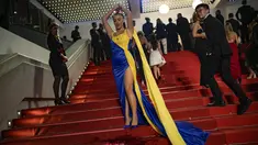 Seseorang dengan warna Ukraina menuangkan zat merah ke tubuhnya pada pemutaran perdana film 'Aside' selama Festival Film Cannes ke-76, di Cannes, Prancis selatan, Minggu, 21 Mei 2023. (AP Photo/Daniel Cole)