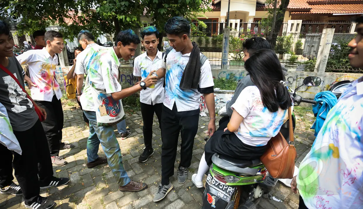 Siswa Sekolah Menengah Kejuruan (SMK) mencoret seragam rekannya usai mengikuti Ujian Nasional (UN) di Jakarta, Kamis (16/4/2015). Aksi tersebut merupakan tradisi para pelajar sebagai bentuk kegembiraan usai mengikuti UN. (Liputan6.com/Faizal Fanani)