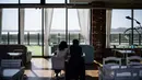 Dalam foto yang diambil pada tanggal 24 April 2025 ini, para pelanggan melihat ke arah pegunungan Korea Utara dari kafe Daonsoop, sebelah utara Seoul, Korea Selatan. (ANTHONY WALLACE/AFP)