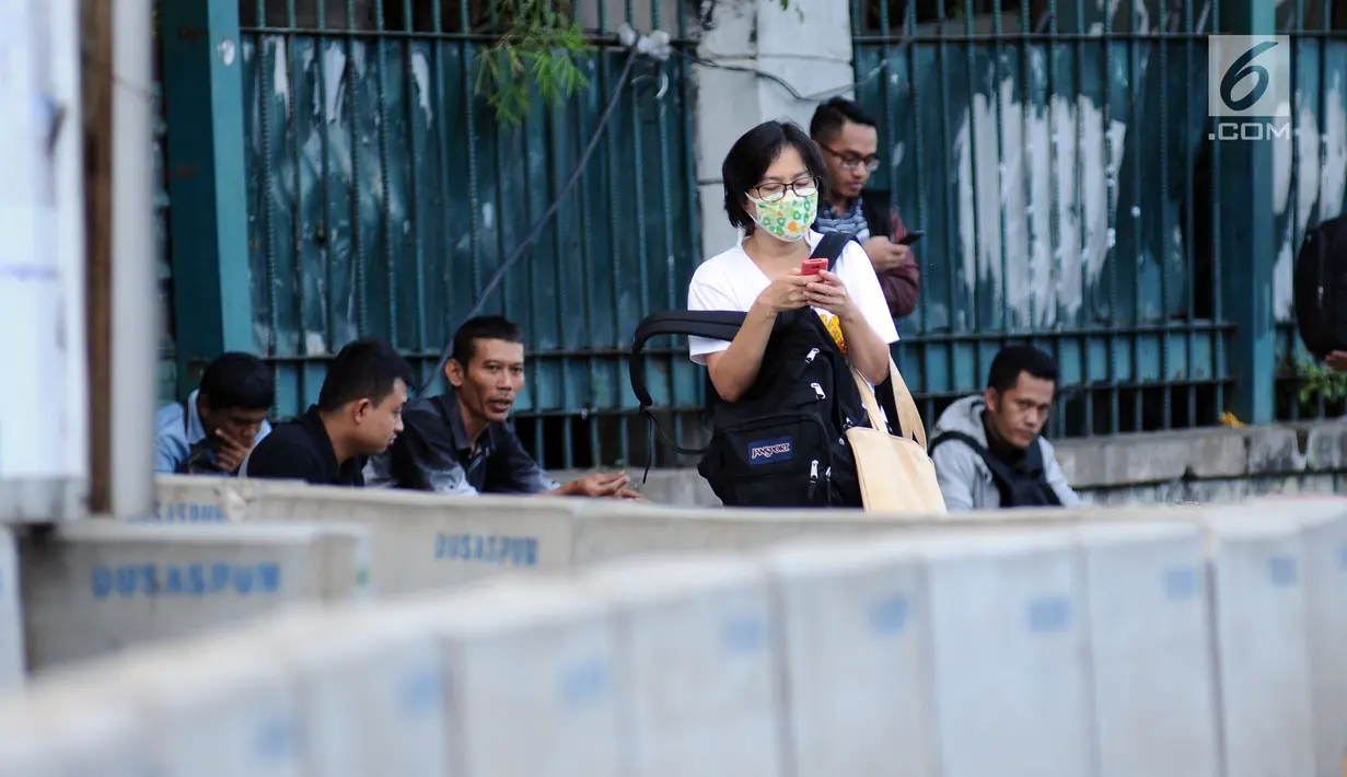Warga menunggu angkutan di pinggir Jalan Jenderal Sudirman, Jakarta, Jumat (14/7). Menurut Kepala Dinas LHK DKI Jakarta Isnawa Adji, kualitas udara yang buruk terjadi di hampir seluruh Jakarta terutama di pusat industri. (Liputan6.com/Helmi Fithriansyah)