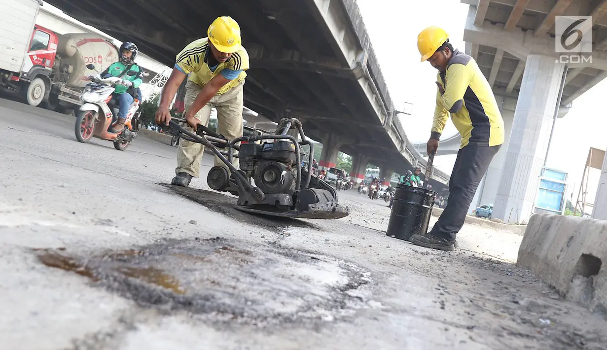 Petugas menambal lubang pada jalan yang rusak di kawasan Jatinegara, Jakarta, Kamis (7/2). Musim hujan yang mengguyur Jakarta selama beberapa waktu terakhir meninggalkan kerusakan pada sejumlah ruas jalan di Ibukota. (Liputan6.com/Immanuel Antonius)