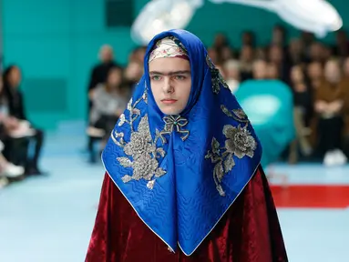 Seorang model dengan scarf menyerupai hijab di kepalanya menampilkan koleksi terbaru Gucci FW18 dalam Milan Fashion Week 2018, Rabu (21/2). Hadirnya model yang memakai scarf menyerupai hijab itu mencuri perhatian. (AP Photo/Antonio Calanni)