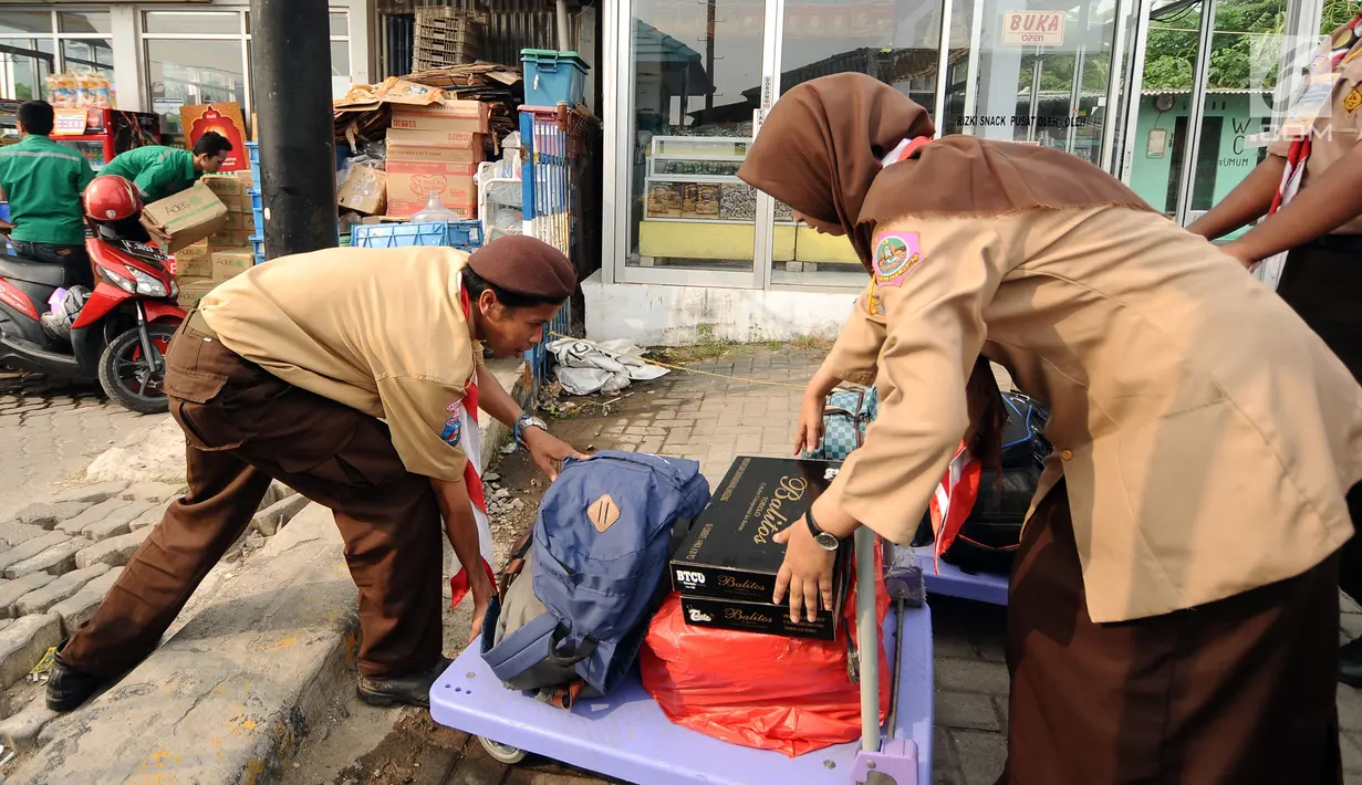 Anggota Pramuka mengangkat troli dan barang bawaan pemudik di kawasan Pelabuhan Merak, Banten, Kamis (22/6). Di Pelabuhan Merak, sejumlah anggota Pramuka diterjunkan untuk membantu pemudik membawa barang bawaan. (Liputan6.com/Helmi Fithriansyah)